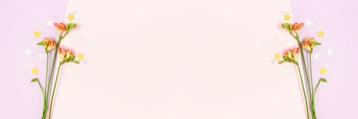 Frame made of freesia flowers and stars confetti. Colorful banner with place for text.