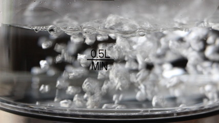 bubbles of boiling water behind glass marked in liters in gray tones