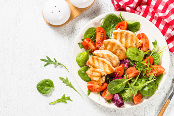 Grilled chicken with fresh salad on white.