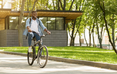 Eco Ride. Happy african american man riding bicycle in city