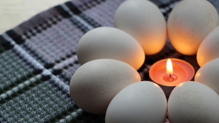 Easter picture with a flower of white eggs with a burning candle in the center