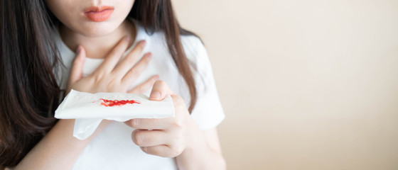 Woman have a coughing up blood and chest pain. Close up of hands holding tissue paper with bloody...