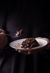 Chocolate fondan on a wthite plate in woman hands