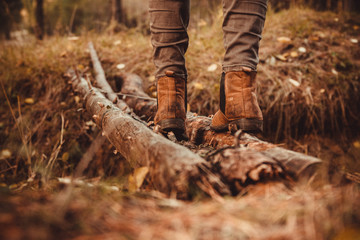 Feet in boots close-up. A life of Hiking and adventure. Crossing the bridge of logs in the woods.
