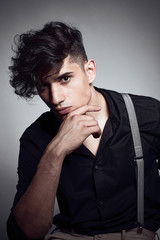 Young guy in a black shirt similar to Adriano Celentano posing on a white background. Fashion portrait