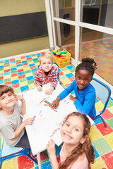 Happy children in kindergarten are painting at the table