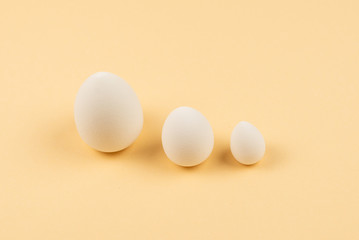 Small, medium and large white beauty blender on beige background.
