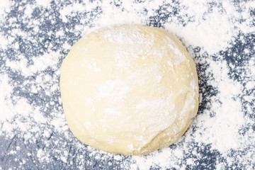 Fototapeta na wymiar Raw round dough with flour top view, copy space, gray background