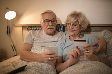 Senior couple buying on the Internet with credit card and mobile phone.