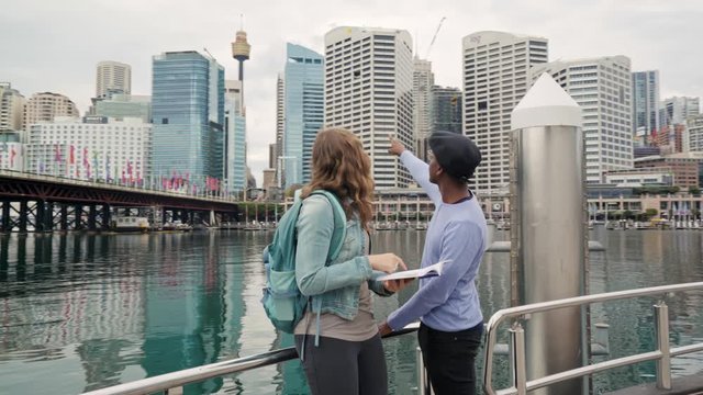 Orbital shot of multi-ethnic friends looking at a tourist guidebook before marveling at the Sydney cityscape 