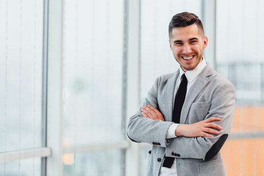 Confident young businessman standing with his hands folded, looking at the camera, ready to hard work day.