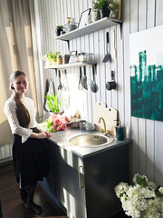 beautiful young mistress in the kitchen. cooking alone in a modern kitchen interior. nice girl near the sink, in the kitchen