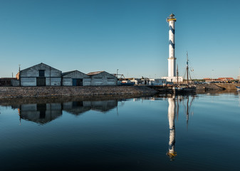 Old lighthouse of Ostend known as ‘Lange Nelle’, reflected in a commercial dock, Thursday 2 August 2018, Oostende, Belgium
