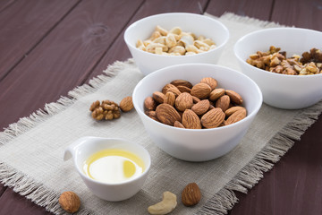 diet food concept, almonds, walnuts and cashew nuts with oil on a wooden table
