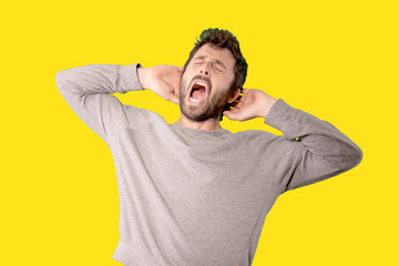 handsome young man with bored expression, feeling frustrated and annoyed, sick and tired of failure, fed-up with dull, boring tasks against yellow background