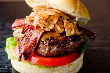 Bacon Cheeseburger with swiss cheese. open faced burger. Traditional classic american restaurant and pub menu item. Cheese burger served with melted swiss cheese lettuce tomato onion and pickle.