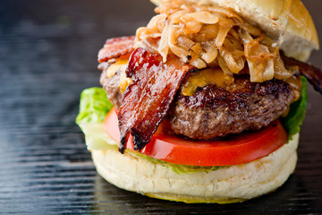 Bacon Cheeseburger with swiss cheese. open faced burger. Traditional classic american restaurant and pub menu item. Cheese burger served with melted swiss cheese lettuce tomato onion and pickle.