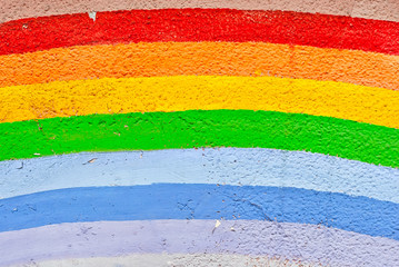 old grungy texture, dirty concrete wall with cracks. Different colors of the rainbow. Rainbow painted with paints on the wall.