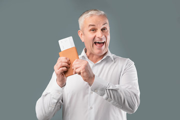 Happy senior man holding tickets and passport