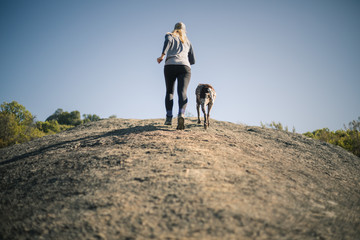 Woman and dog running up a hill