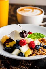 Granola, yogurt and fresh fruit. Traditional classic American restaurant or French bistro favorite menu item. Crunchy granola, yogurt, blueberries, strawberries, topped with mint