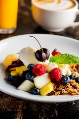 Granola, yogurt and fresh fruit. Traditional classic American restaurant or French bistro favorite menu item. Crunchy granola, yogurt, blueberries, strawberries, topped with mint