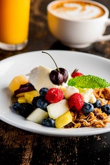 Granola, yogurt and fresh fruit. Traditional classic American restaurant or French bistro favorite menu item. Crunchy granola, yogurt, blueberries, strawberries, topped with mint
