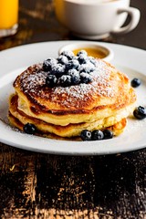 Pancakes. Homemade blueberry buttermilk pancakes. Classic Traditional American breakfast or brunch favorite. Topped with fresh berries, sugar and maple syrup. 