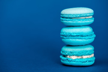 Fototapeta na wymiar tasty french macaroons on blue background with copy space