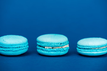 tasty french macaroons on blue background with copy space