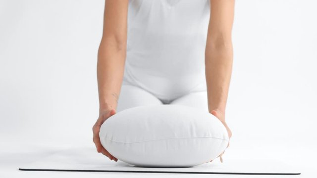 unrecognizable woman in white space practice yoga put a yoga pillow towards to the camera