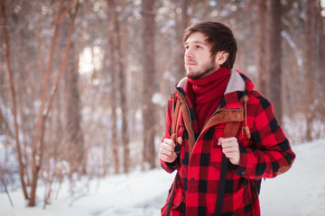 Male tourist with backpack walks on snow pine forest. Guy hiking at nature. Concept of winter holiday or vacation..