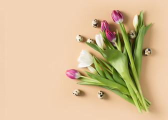 Tulips easter flat lay with pink and white flowers bouquet and eggs on beige background
