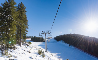 Snowy ski slopes and chair ski lifts station in  mountain ski resort.