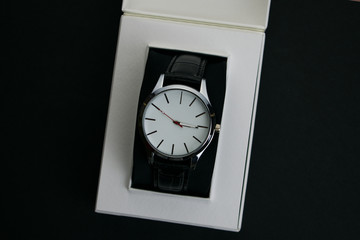 Wristwatch in a red box on a dark background.Watch in a case on a black velvet pillow
