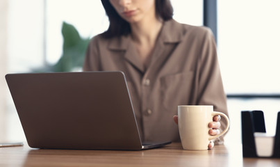 Portrait of focused woman working on laptop with coffee