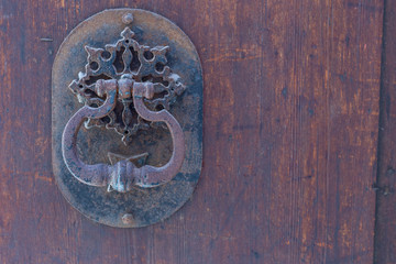 old metal door handles with a beautiful metal ornament on a wooden background