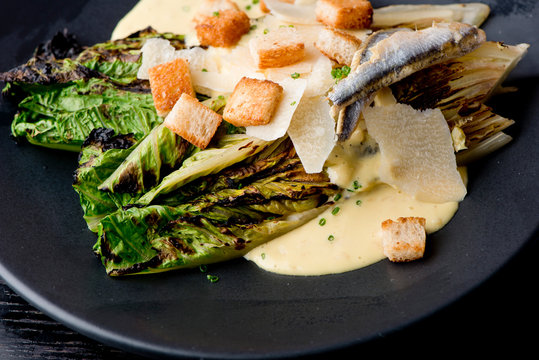 Caesar Salad. Grilled Romaine Lettuce Leaves Topped With Classic Caesar Salad Dressing And Garnished With Butter Garlic Croutons Shaved Parmesan Cheese And Whole Anchovies. Classic American Salad.