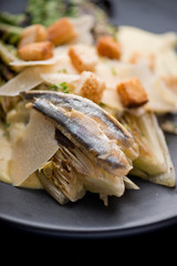 Caesar Salad. Grilled Romaine lettuce leaves topped with classic Caesar salad dressing and garnished with butter garlic croutons shaved parmesan cheese and whole anchovies. Classic American Salad.