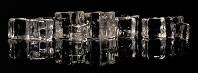 Ice cubes in a row on a black mirror surface with reflections isolated on black background.