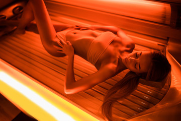Beautiful young woman tanning skin treatment in modern solarium