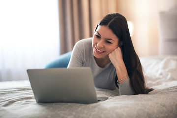Naklejka premium Beautiful woman using laptop on her bed.