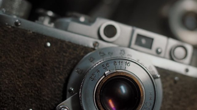Lens with aperture values of old vintage photo camera, smooth cinematic motion, close up. Chrome surface reflects light, slow rotation movement.