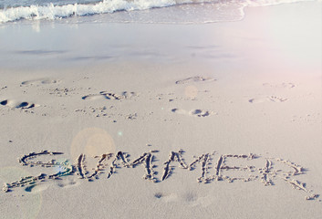 Summer time and word written in sand during a seaside holiday.  Copy space.