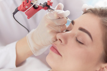 A young girl having red lips permanent makeup, micropigmentation