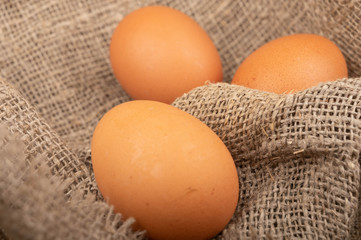 Chicken eggs on a background of rough homespun fabric. Country food. Close up.