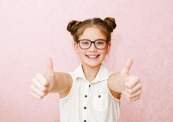 Portrait of funny smiling little girl child wearing glasses with two fingers up isolated - 327826545