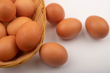 Chicken eggs in a wicker basket and eggs scattered on a white background. Close up.