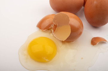 A broken chicken egg and several eggs on a white background. Close up.