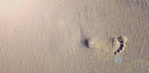 Small footprint of child  in the sand during summer holiday. Space on sand with sun. Copy space. 